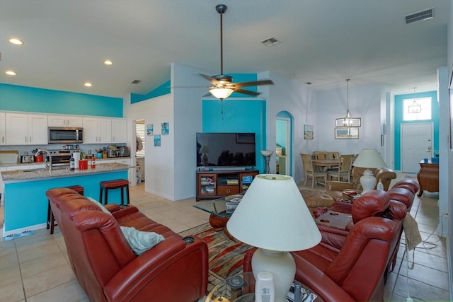 living room featuring light tile patterned floors, vaulted ceiling, sink, and ceiling fan