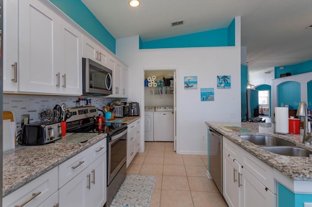 kitchen featuring lofted ceiling, sink, independent washer and dryer, stainless steel appliances, and white cabinets