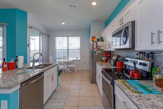 kitchen with light tile patterned flooring, sink, appliances with stainless steel finishes, white cabinets, and backsplash