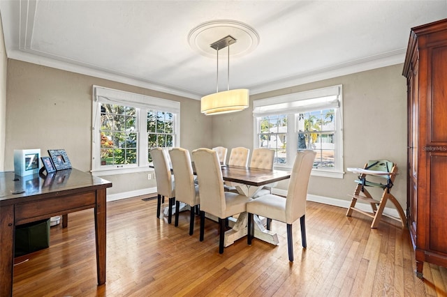 dining space with ornamental molding and light hardwood / wood-style floors