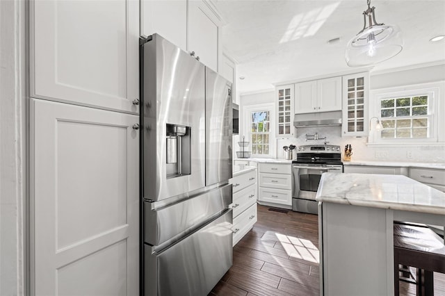 kitchen with appliances with stainless steel finishes, white cabinets, a kitchen bar, and decorative light fixtures