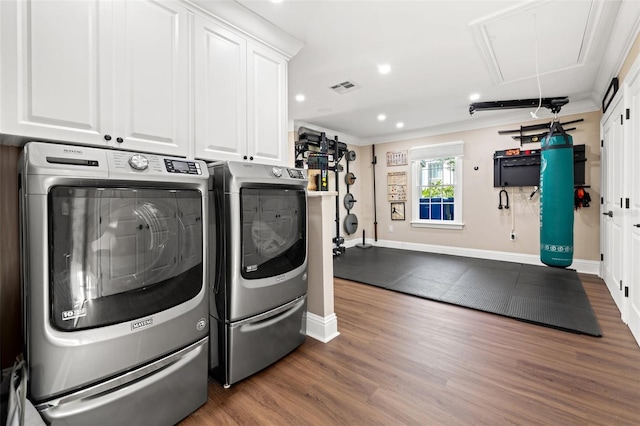 laundry room with crown molding, cabinets, hardwood / wood-style floors, and washer and dryer