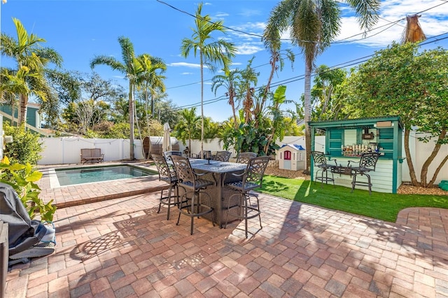 view of patio / terrace featuring a fenced in pool and a storage shed