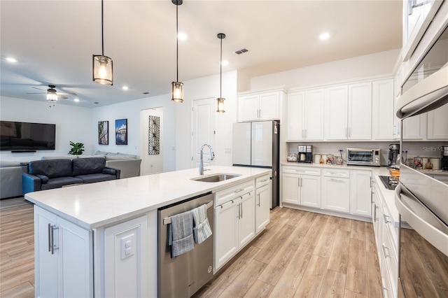 kitchen with a kitchen island with sink, sink, white cabinets, and appliances with stainless steel finishes