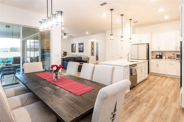 dining space featuring ceiling fan, sink, and light hardwood / wood-style flooring