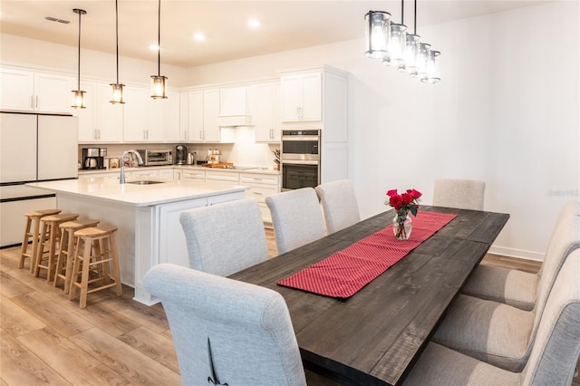 dining space with sink and light wood-type flooring