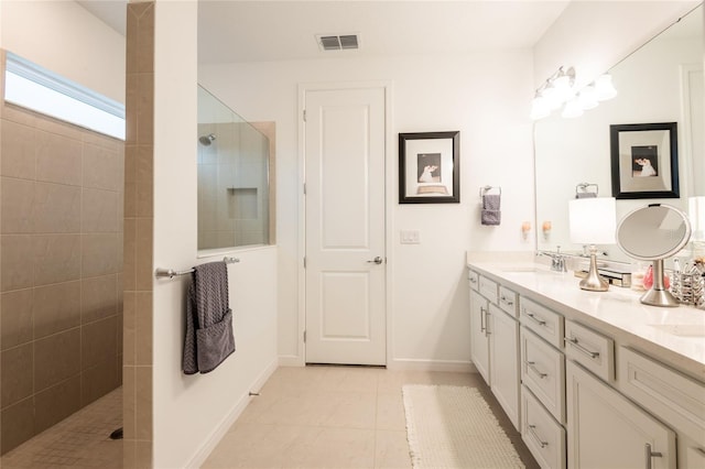 bathroom with tile patterned flooring, vanity, and tiled shower