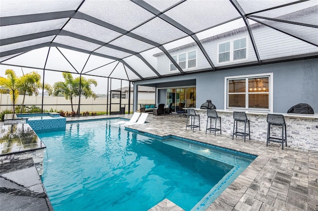 view of pool featuring an in ground hot tub, a patio area, an outdoor bar, and glass enclosure