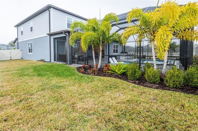 rear view of house featuring a lanai and a lawn