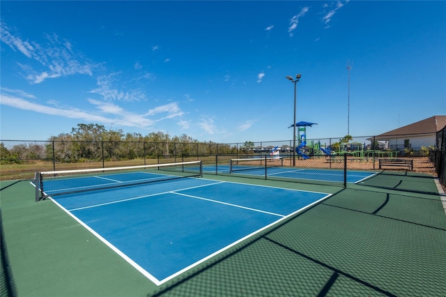 view of tennis court featuring a playground