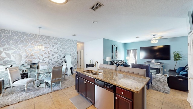 kitchen featuring dishwasher, an island with sink, sink, light tile patterned floors, and ceiling fan