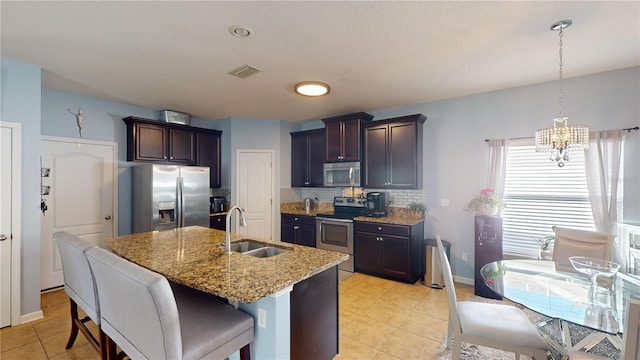 kitchen featuring appliances with stainless steel finishes, a kitchen island with sink, sink, and dark brown cabinets