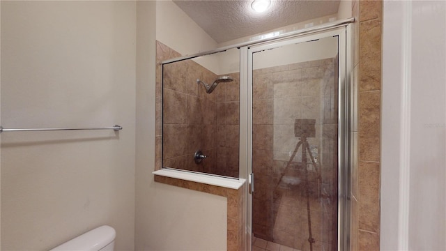 bathroom with a textured ceiling, toilet, and walk in shower