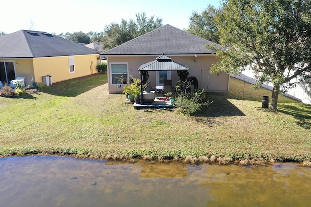 rear view of property featuring a gazebo, a water view, and a yard