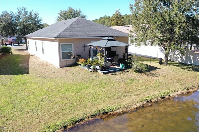 back of house featuring a gazebo, a water view, and a yard