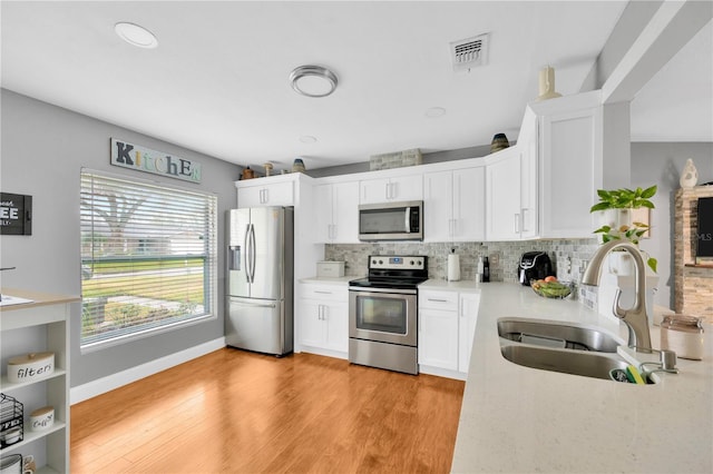 kitchen with white cabinetry, appliances with stainless steel finishes, sink, and light wood-type flooring