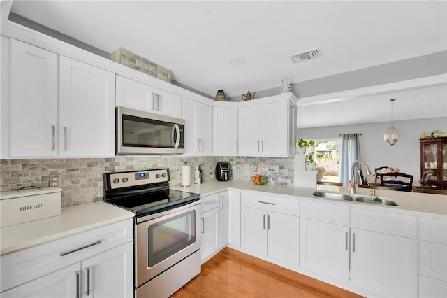 kitchen with decorative light fixtures, white cabinetry, sink, decorative backsplash, and stainless steel appliances