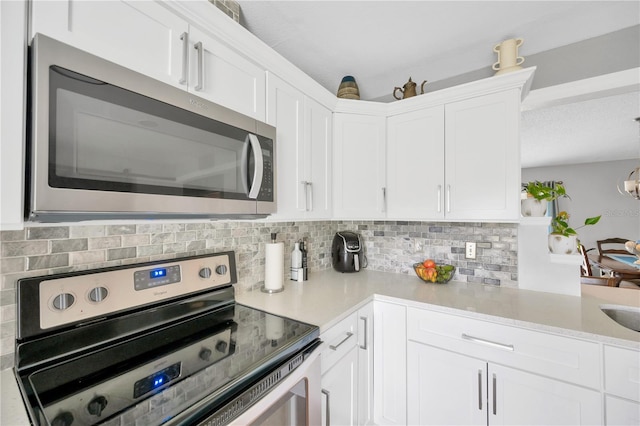 kitchen with stainless steel appliances, tasteful backsplash, and white cabinets