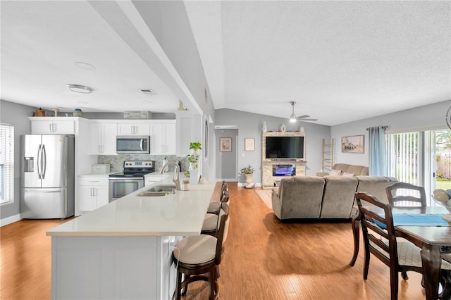 kitchen featuring sink, a breakfast bar area, stainless steel appliances, white cabinets, and decorative backsplash