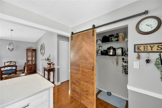 kitchen featuring white cabinetry, an inviting chandelier, decorative light fixtures, light wood-type flooring, and a barn door