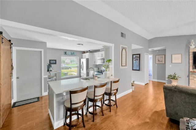 kitchen featuring white cabinetry, a kitchen breakfast bar, kitchen peninsula, stainless steel appliances, and a barn door