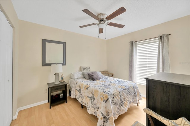 bedroom with light wood-type flooring, ceiling fan, and a closet