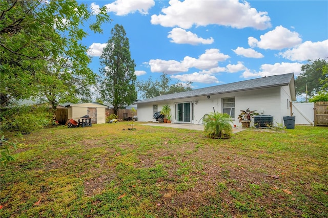 rear view of property featuring central AC unit, a patio area, a shed, and a lawn