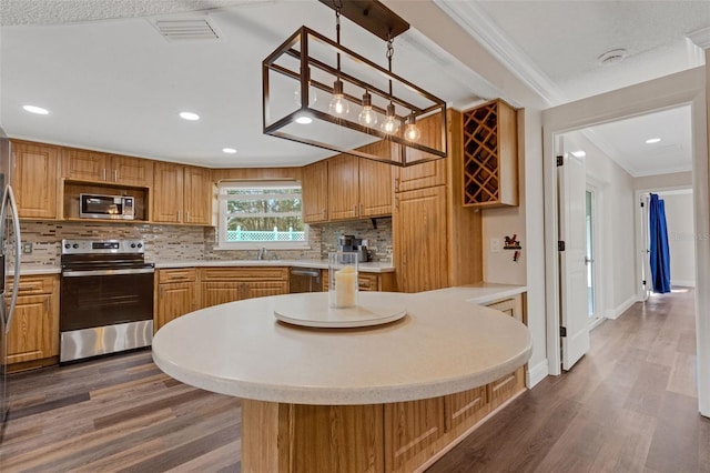 kitchen with appliances with stainless steel finishes, tasteful backsplash, hanging light fixtures, crown molding, and dark wood-type flooring