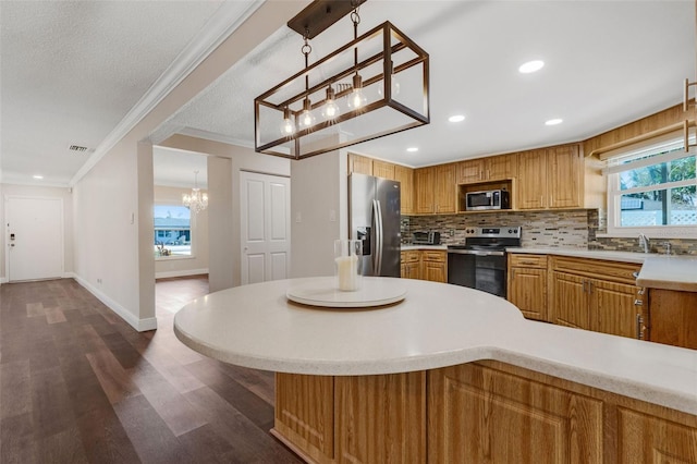 kitchen with hanging light fixtures, backsplash, a healthy amount of sunlight, and appliances with stainless steel finishes