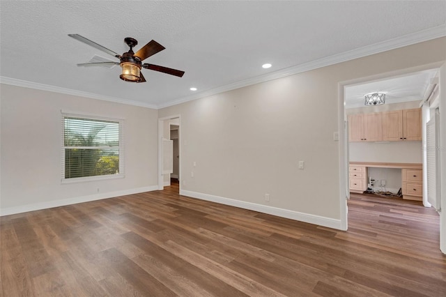 empty room featuring crown molding, ceiling fan, dark hardwood / wood-style floors, built in desk, and a textured ceiling