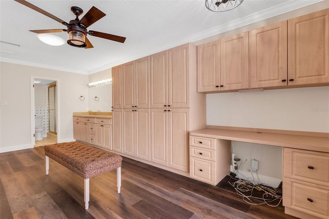 unfurnished office with crown molding, ceiling fan, dark hardwood / wood-style floors, built in desk, and a textured ceiling