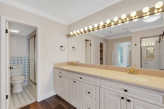 bathroom with hardwood / wood-style floors, vanity, ornamental molding, a shower with shower door, and toilet