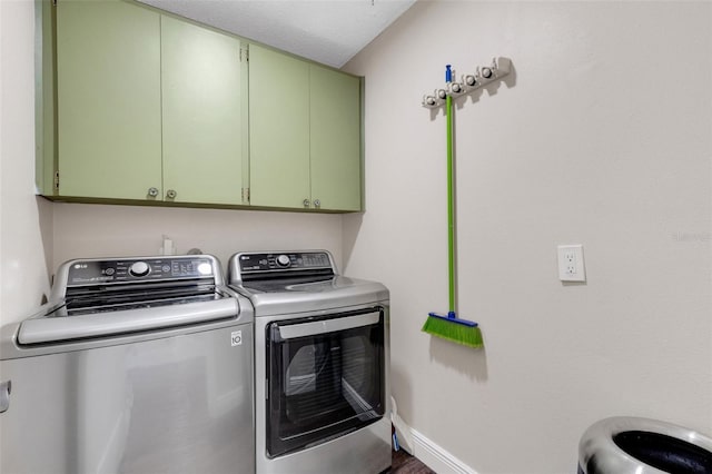 clothes washing area with washer and dryer and cabinets