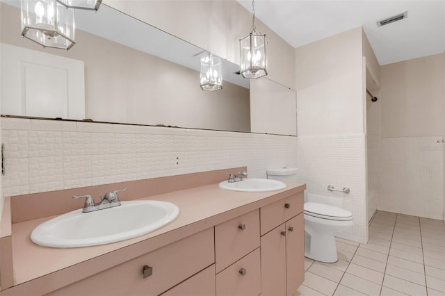 bathroom with tile patterned flooring, vanity, toilet, and tile walls