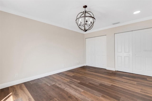 unfurnished bedroom with multiple closets, ornamental molding, an inviting chandelier, and dark wood-type flooring