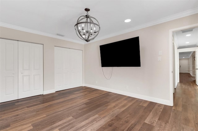 unfurnished bedroom with multiple closets, ornamental molding, dark hardwood / wood-style floors, and an inviting chandelier