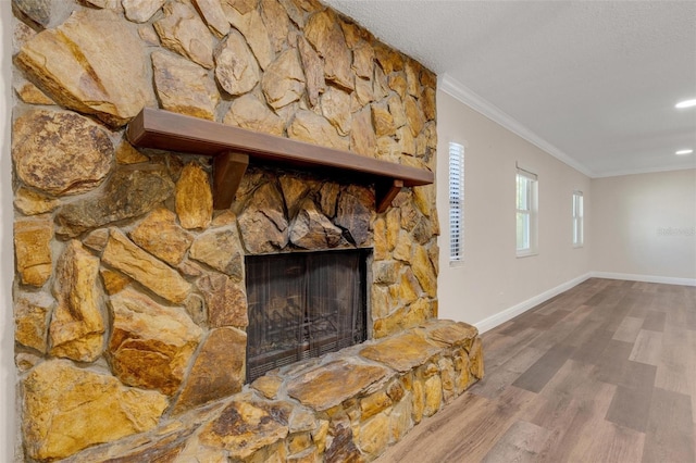 unfurnished living room with crown molding, a fireplace, a textured ceiling, and hardwood / wood-style flooring