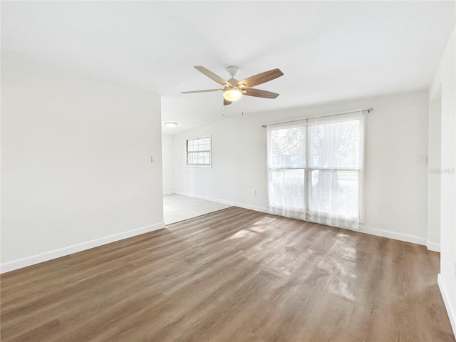 empty room with hardwood / wood-style flooring, lofted ceiling, and ceiling fan