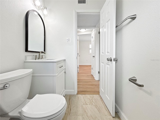 bathroom with vanity, toilet, and hardwood / wood-style floors