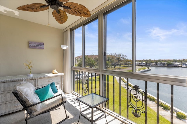 sunroom featuring a water view and a ceiling fan