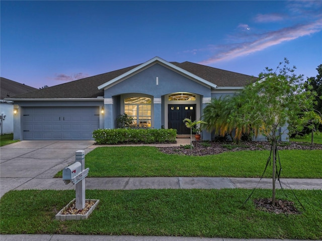 ranch-style house with a garage and a yard