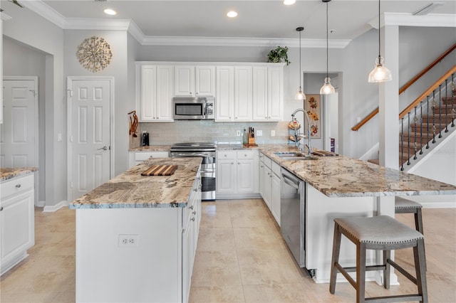 kitchen with a kitchen island, decorative light fixtures, sink, light stone counters, and stainless steel appliances