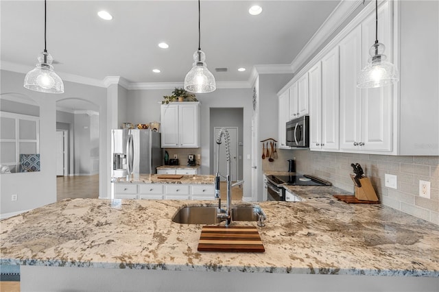 kitchen with hanging light fixtures, sink, white cabinets, and appliances with stainless steel finishes