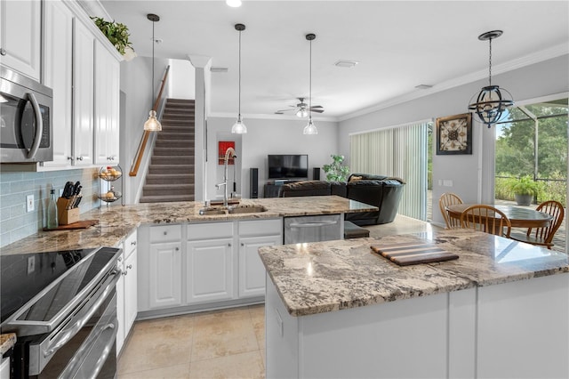 kitchen with sink, stainless steel appliances, white cabinets, a kitchen island, and decorative light fixtures