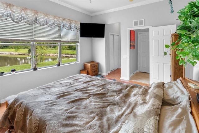 bedroom with ornamental molding, a water view, and a closet