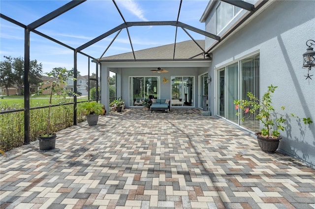 view of patio with ceiling fan, an outdoor hangout area, and glass enclosure