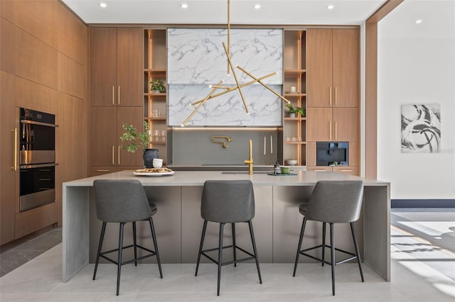 kitchen featuring light tile patterned floors, stainless steel double oven, a kitchen bar, built in shelves, and a large island with sink