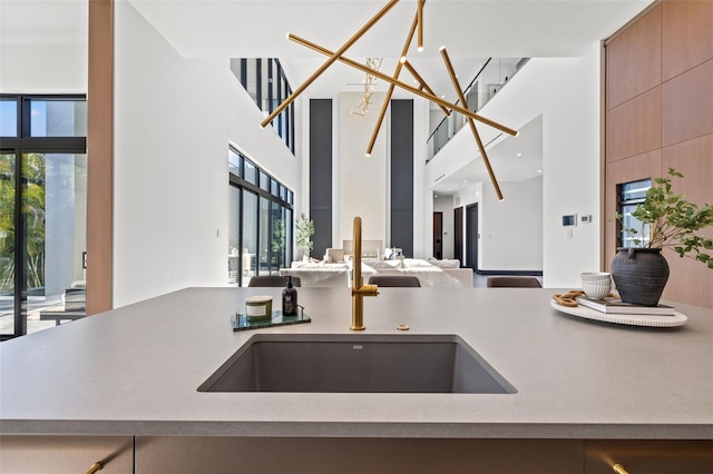 kitchen featuring a towering ceiling, a chandelier, and sink
