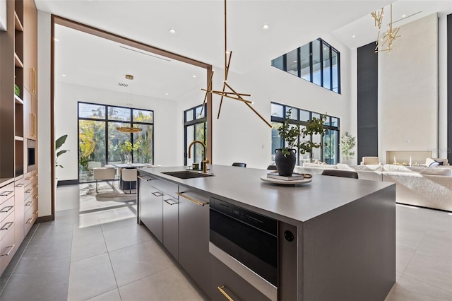 kitchen featuring sink, a spacious island, light tile patterned flooring, decorative light fixtures, and oven