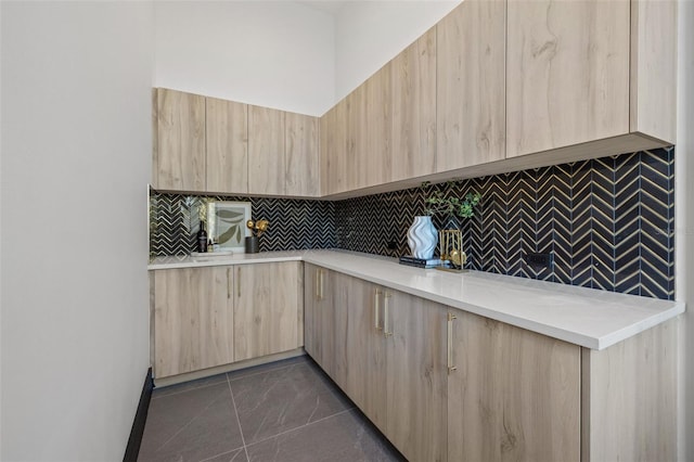 kitchen with tasteful backsplash, dark tile patterned flooring, and light brown cabinets